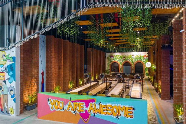 The indoor area has been curated with a strong influence of architectural features within the space in the form of voided ceilings, suspended greenery, brick column features & arched openings adorned with custom artwork. The space mimics the feel of an indoor-outdoor plaza. 