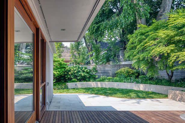 A curved concrete retaining wall embraces the patio and lawn