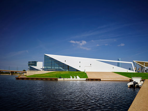 The east elevation is parallel to a river inlet allowing rowing shells to access the river via a concrete ramp. The inlet size allows for a 60’ long boat to maneuver. The open beam frames Downtown. The gold “notes” are rhythmically placed on the façade. 