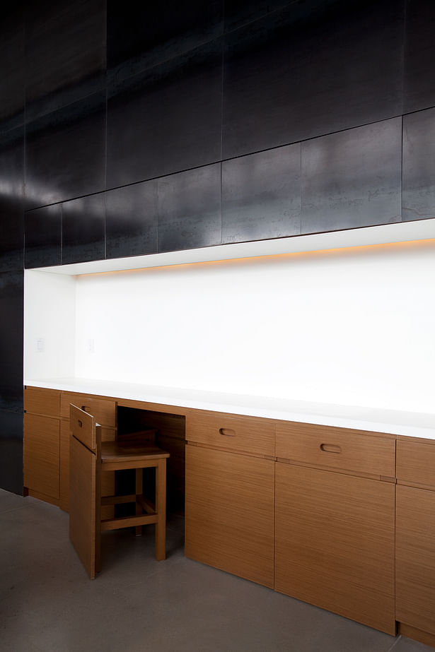 Extra seating is hidden under sleek countertop within the storage wall. 