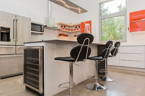 A wine cooler is tucked into the end of the kitchen island. 