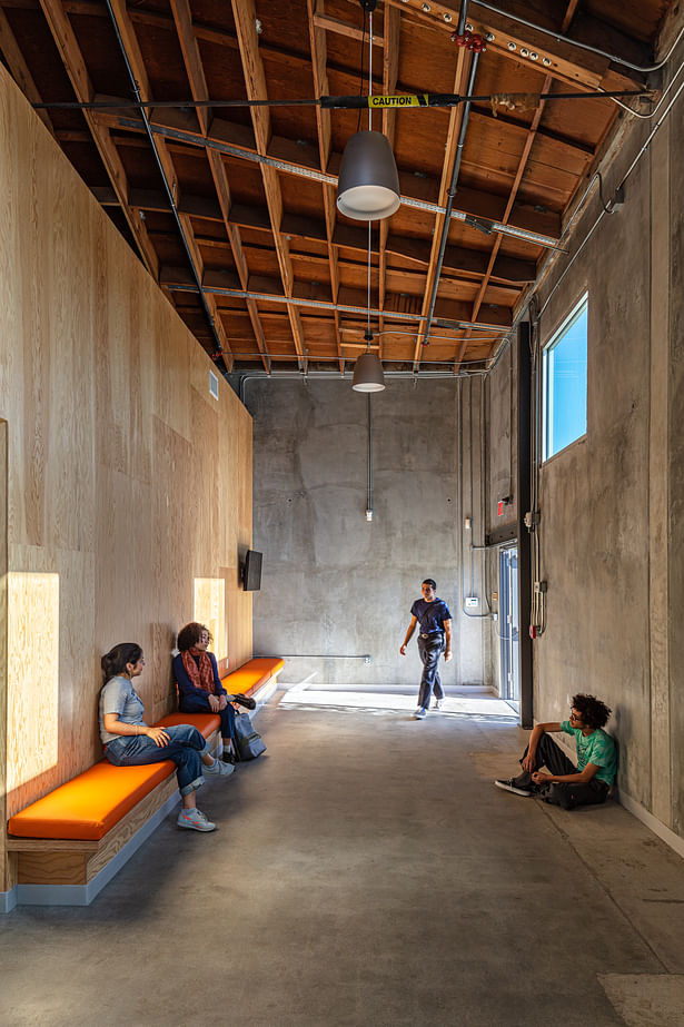 The entry lobby, with exposed ceilings, concrete walls polished to enhance their textures, and a bench where students can gather before and after class.