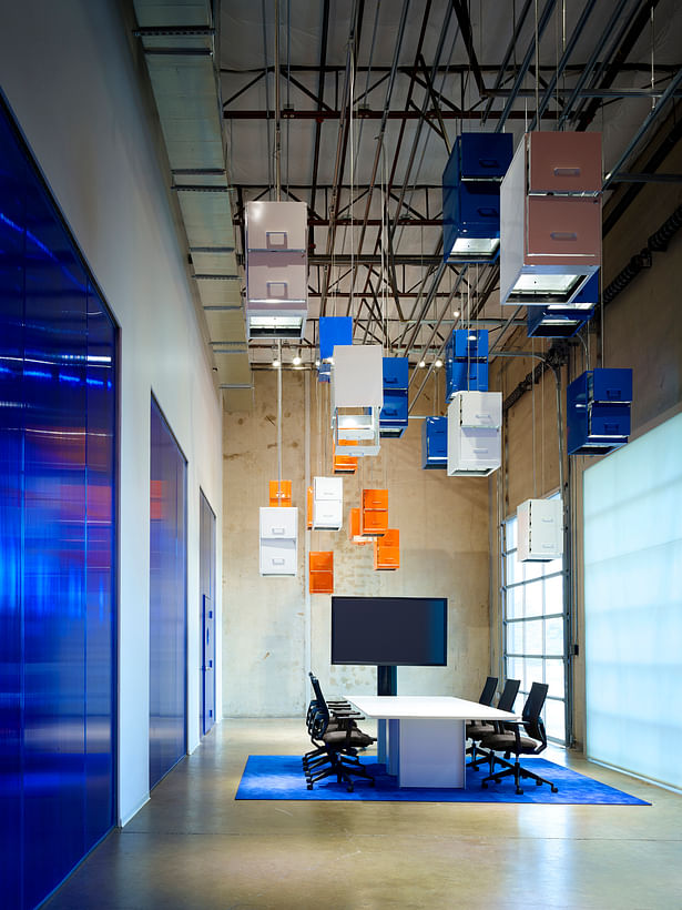 The original delivery dock is transformed into a primary conference and presentation space. A “cloud” made of pre-owned filing cabinets suspended from the ceiling represent the transition from paper-based systems to storing information digitally in the cloud. 