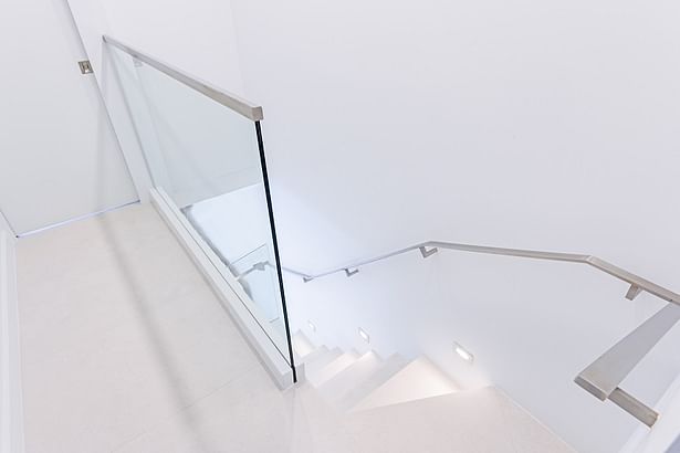 A glass guardrail was also installed on the second floor. This glass panel was top mounted to an aluminum base shoe, then covered with a white coated stainless steel cladding to match seamlessly with the flooring.