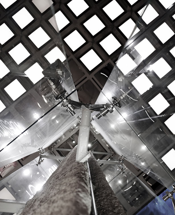 A close-up detail of the column, glass support and the waffle ceiling beyond.