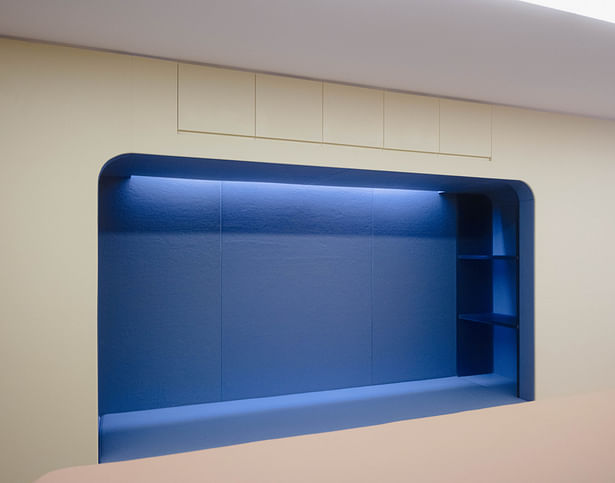 A wide seating nook overlooking the tunnel room with storage cabinets above. 