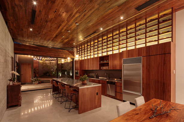 The kitchen space takes on a more modern lighting experience, illuminating the overhead wall holding the client's wine.