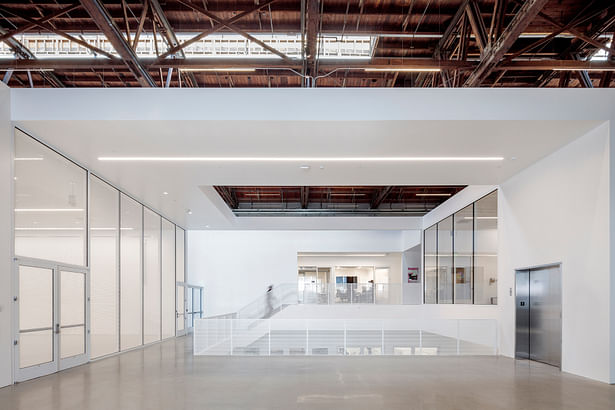 This image from the mezzanine shows the sectional hole with offices beyond (middle) as well as a flexible lecture / gallery space (left) and studio window (right). | Credit: Joshua White (jwpictures.com)