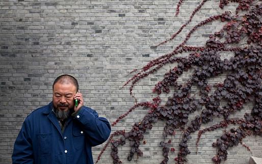 Ai Weiwei talks on his mobile phone at his studio in Beijing. (Aeon; Photo by Adam Dean/Panos)