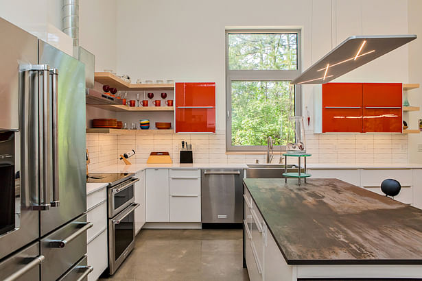 The kitchen is an exercise in simplicity, including natural wood open shelving above Silestone counters.