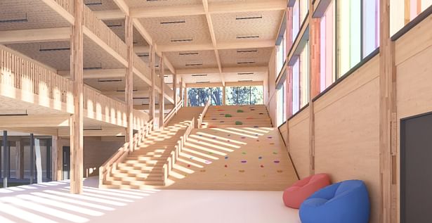 The lobby features exposed timber and a climbable rockwall and seating area integrated into the stairs. Natural light enters through all sides of the entry.