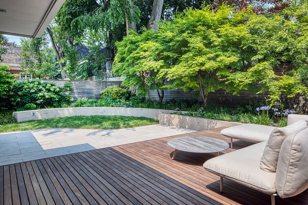 Curved concrete retaining walls separate the tiered planting beds from the open areas of the garden