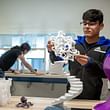 A student in the Fab Lab holds a 3-D printed object. Image courtesy of NYIT School of Architecture and Design