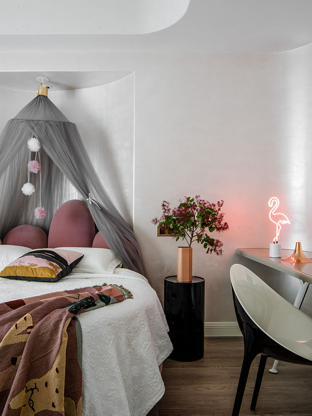 Compared to the white wall, the lacquer texture can enlarge the brilliance of the art wall surface. The pink-pink bed and rug give the space a personality and temperature.