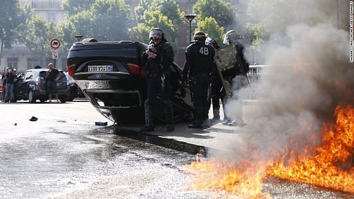 French policemen standing near a car that was overturned during riots by taxi drivers in protest of UberPop. Credit: Thomas Samson / AP