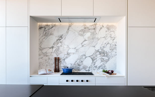This stunning Calacatta Vagli marble is the perfect color and feeling for this cooktop niche…A perfect balance of soft white backdrop with an astonishing grey veining. It took one whole slab and 5 men to install it. It also has a simple, architectural light channel providing dramatic evening mood light.. © David Lauer Photography