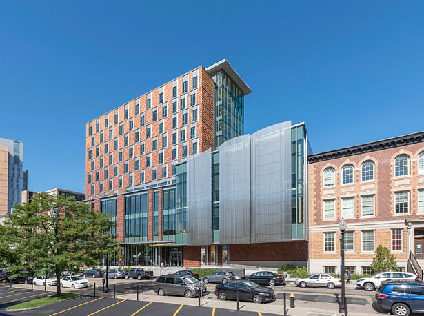 The base of the Student Life and Performance Center aligns with the cornice of the adjacent St. Botolph Building, which houses the NEC Opera Department. The seven-story residential tower is clad in offset, operable windows and variegated terracotta tiles applied in mixed, rhythmic patterns. Expansive glazing at the lower levels erases the boundary between the street and interior spaces. The performance podium shimmers with stainless steel screen cladding and offers tantalizing glimpses of the...