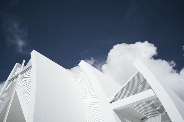 White radius concrete facade and layer of curve wing walls with the natural blue sky of Samui island. photo crt :Peerapat Wimolrungkarat © JUTI architects 