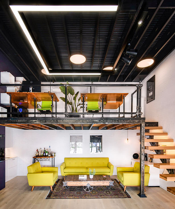 The mezzanine floor splits the space into two functional zones: a computer work space upstairs and a meeting space/lounge downstairs, with a portable bar and micro kitchenette to surpass formality and increase flexibility of working process.