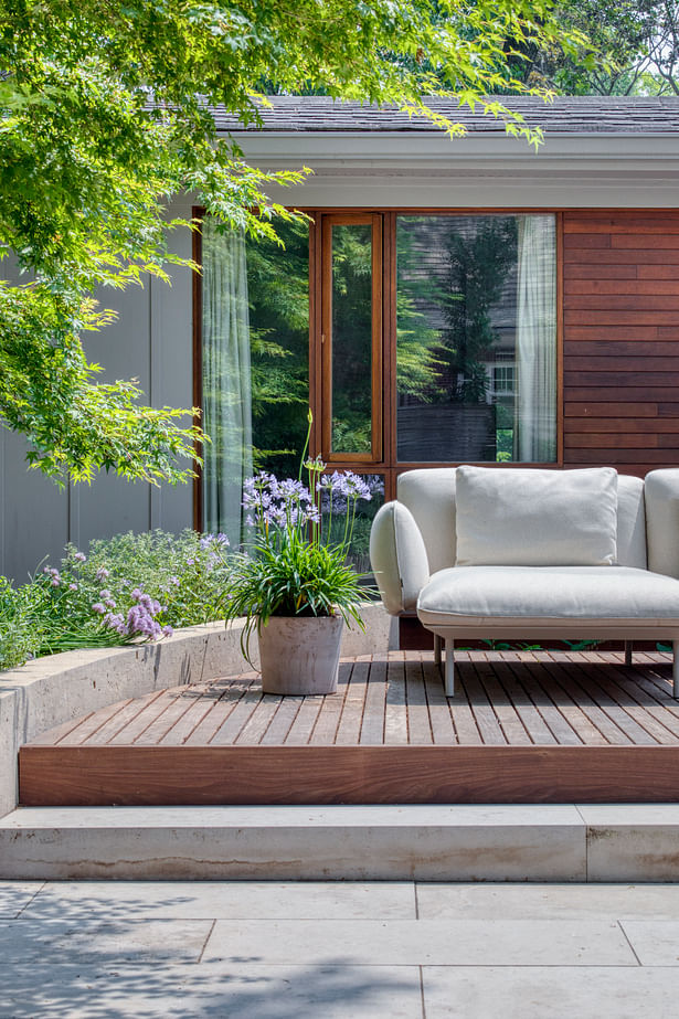 A curved retaining wall frames the deck and outdoor living room