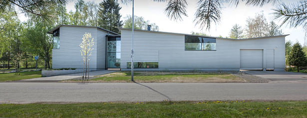 The house has a long street facing facade, and its layout resembles the letter E. The narrow partitions are the glazed stair well on the left and the partition between the house and the garage on the right. Photo by Arno de la Chapelle.