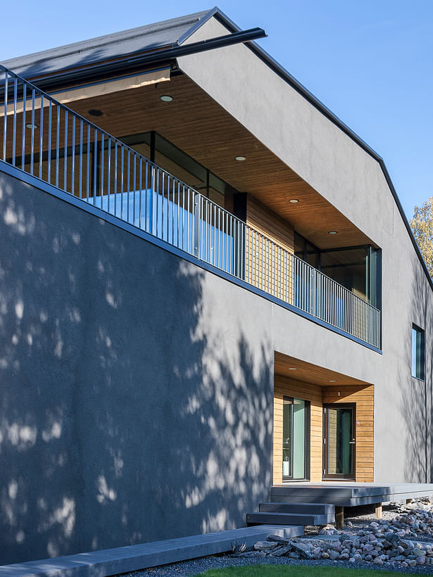 The exterior of the house features glass, grey plaster and warm wood. Photo by Arno de la Chapelle.