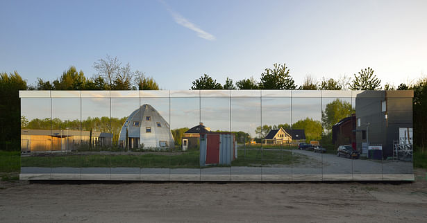 The street facade has a secret window behind the glass panels, with a view of the street and neighboring plots