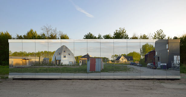 The street facade has a secret window behind the glass panels, with a view of the street and neighboring plots