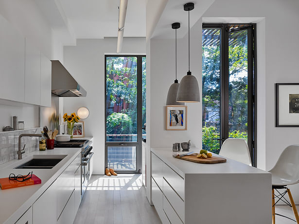 Sun-filled kitchen with french doors and clean white cabinetry leads out to the patio.