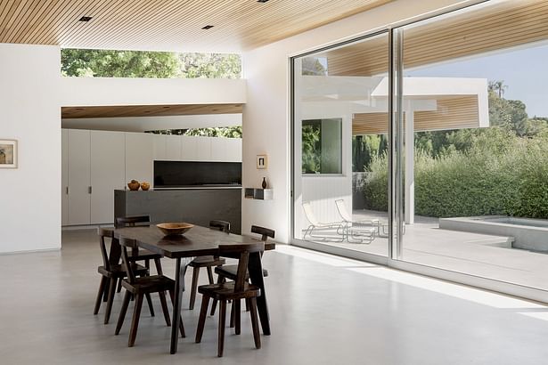 'Inside, the butterfly roof marks much of the interior as well, with ceilings clad in the same cedar siding. A fireplace originally divided what is now one large, open great room complete with expansive sliding glass doors that overlook a patio and pool.'