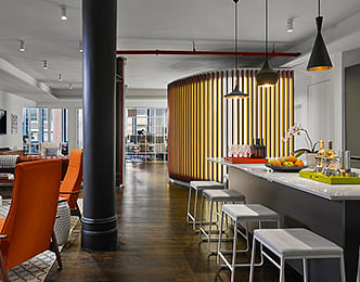 The central shared space utilizes eclectic mid-century modern furniture to divide the space, and a large kitchen island doubles as an informal conference table.