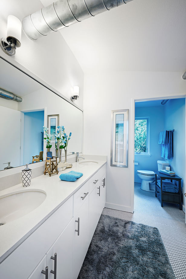 This basic bathroom layout is simple by design, but cohesive in material selections, and allows plenty of natural light via its window that looks onto an undevelopable forested property directly next door.