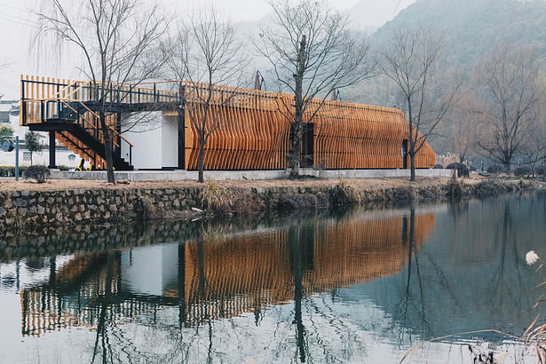 View towards the Centre from across the river. The cedar fins dematerialise allowing views through the interior. Photograph by Li Zhang.