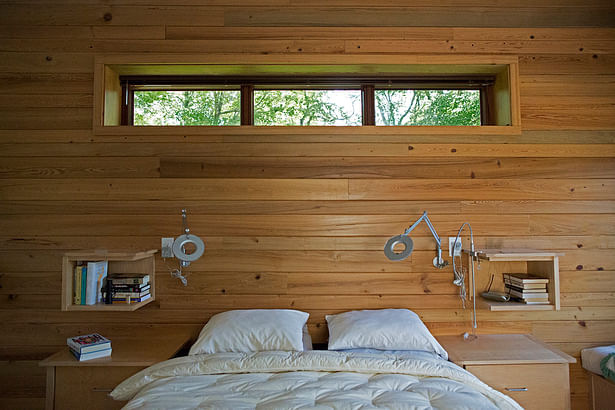 Natural wood covers an entire wall in the master bedroom. The architect designed the wall-mounted bedside shelves.