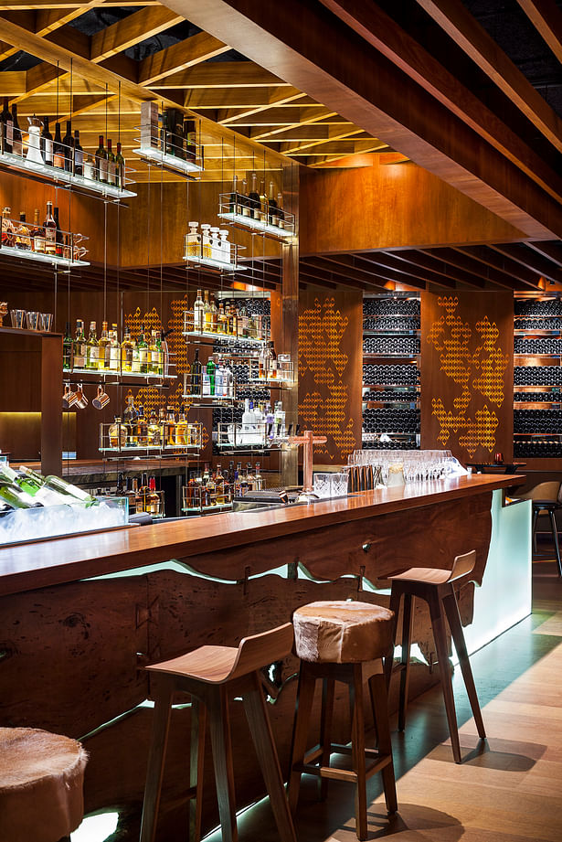 Detail: Island Bar with centre floor-to-ceiling bronzed structurally tensioned stainless steel cable, electrified bottle shelving.