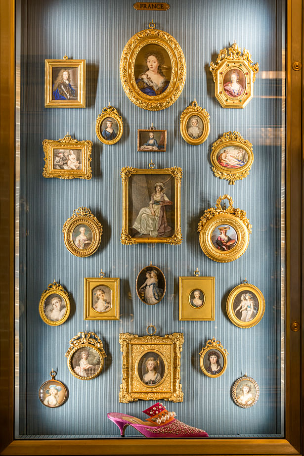A number of shoes are situated within miniature portrait cabinets