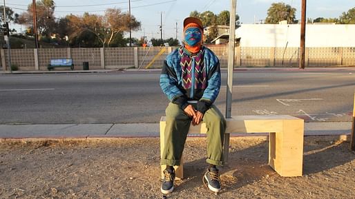 The anonymous artist sitting on a bus-stop bench he installed. Photo credit: Carolina A. Miranda/Los Angeles Times.