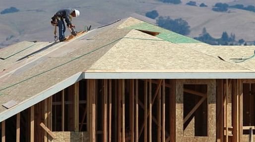 A construction worker cuts a piece of wood on the top of a home under construction at a new housing development in Petaluma, Calif. (Justin Sullivan/Getty Images via marketplace.org)