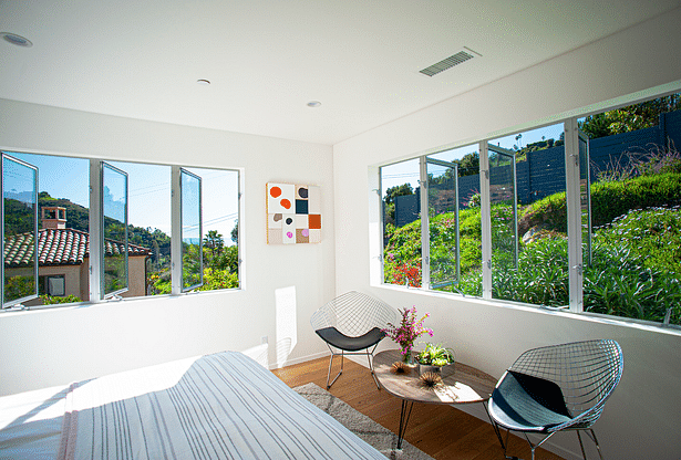 The master bedroom looks out at the ocean while appearing to be nestled in the hillside