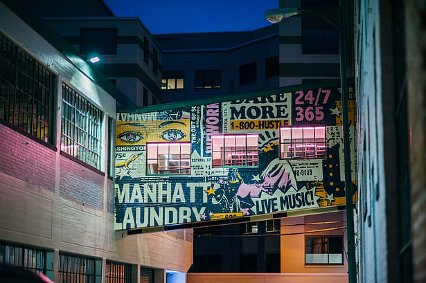 Sky bridge mural referencing the building name, local gogo-music flyers, and WeWork branding