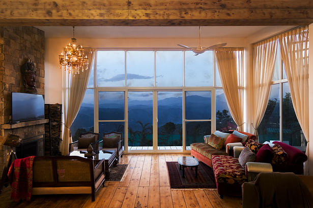 Living area on the left, and textured day beds towards the right, overlooking towards the blue mountanous landscape.