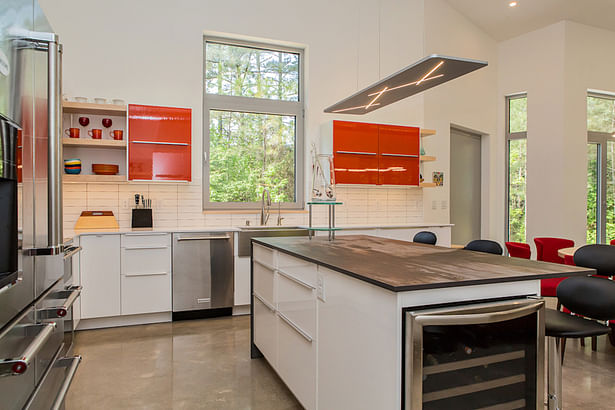 High-gloss flat-slab frameless cabinets and a white subwa tile backsplash add an “industrial” ambience to the kitchen.