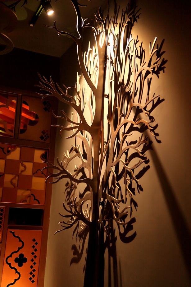 A tree made for stainless steel sheets forming an enhancing night outdoor garden area.