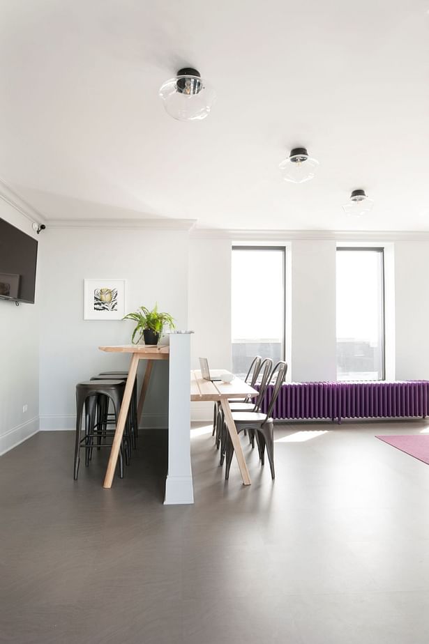 Toward the front of the room, an awkward notch in the wall creates an opportunity for a semi-enclosed work space. Buzzi space “picnic” tables at offset heights provide two layers of function paired with seating in an iron black. The half-wall is capped with the same violet veined marble.