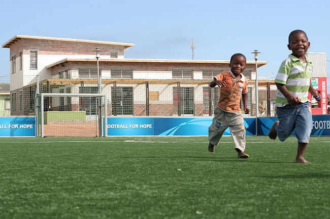 Young children running on the pitch of the Khayelitsha Football for Hope Center, the first completed Football for Hope Center. Location: Cape Town, South Africa. Credit: A. Grips