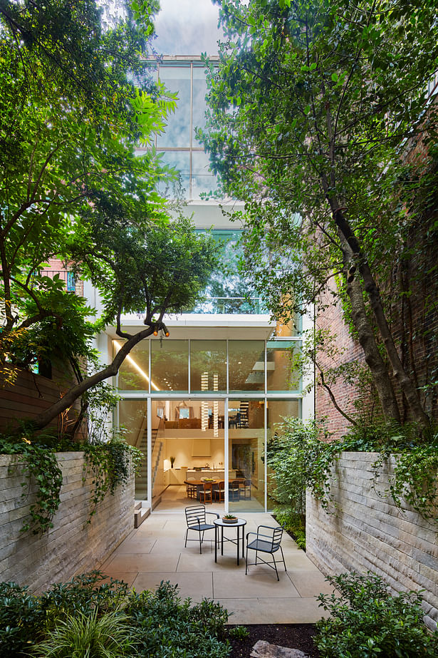 A five-story glass façade opens the house’s living spaces to the rear garden and the sky.