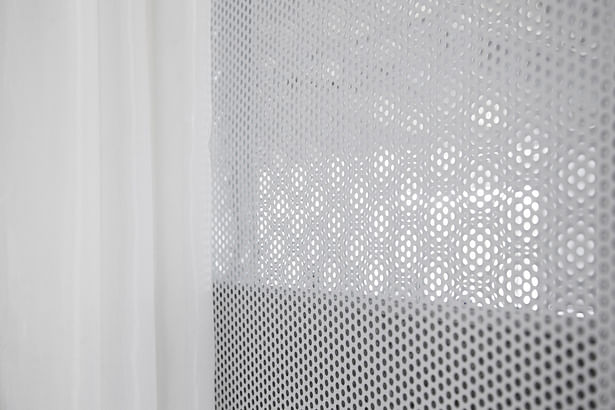 'Soft' conference room walls are built with perforated metal mesh embedded with acoustic cellulose panels for sound absorption. A window area is cut out to let surrounding light into the room.