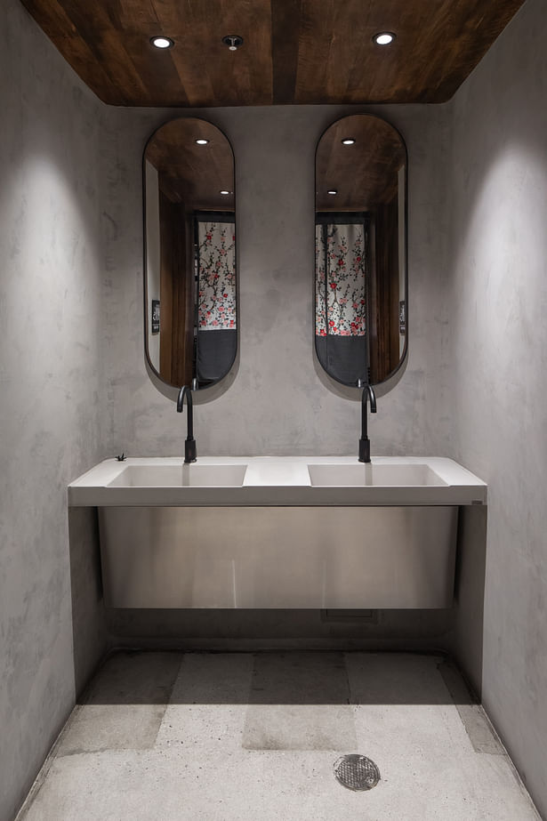 The concrete curving walls enclose the semi-private bathroom amenities.