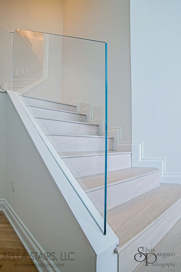 Starphire glass panels were anchored using a stainless steel standoff system, then later covered in drywall to give the illusion of a frame-less glass railing protruding from the ground.