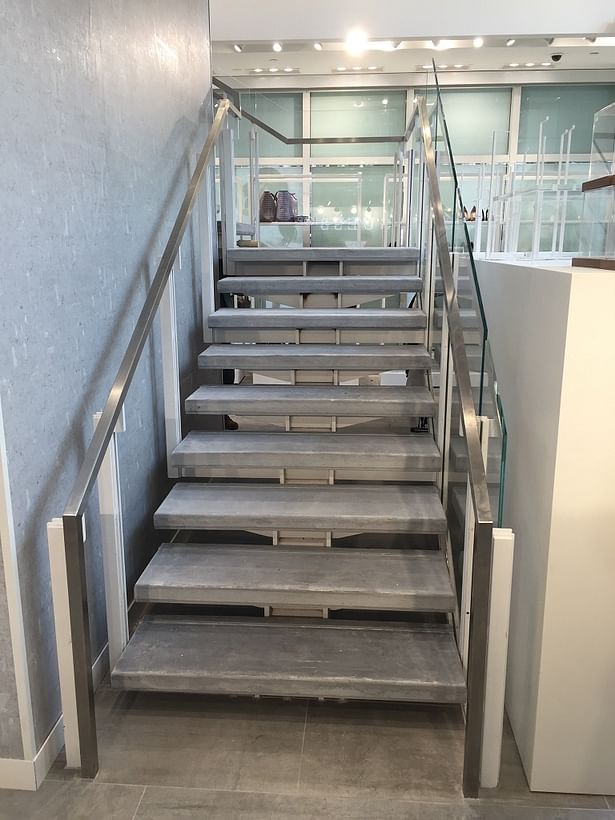 Commercial center beam staircase featuring glass railings and a stainless steel handrail.